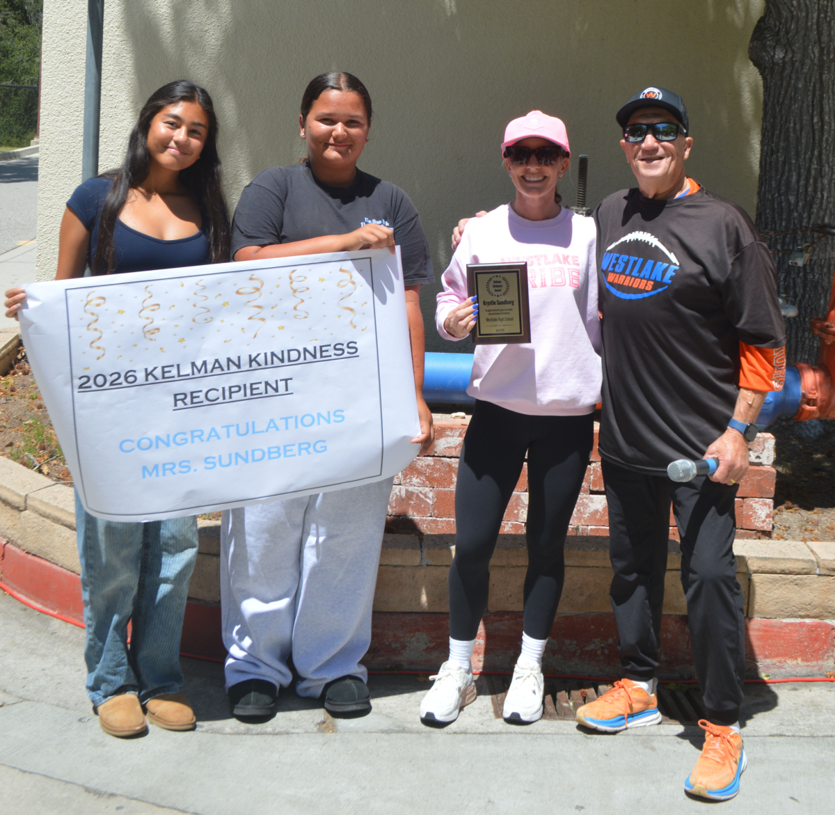 BESTOWALS: After a warm hug and many congratulations, Kelman and Sundberg posed with ASG students Amelie Ortiz ‘28 (left) and Alexis Broadhead ‘28 (right), proudly displaying the plaque and celebratory poster. 